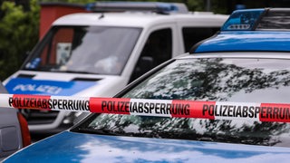Polizeifahrzeuge hinter Polizeiabsperrband mit Aufschrift Polizeiabsperrung