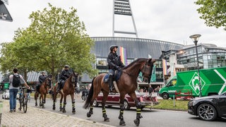 Mehrere Polizistinnen reiten auf Pferden vor dem Weser-Stadion entlang.