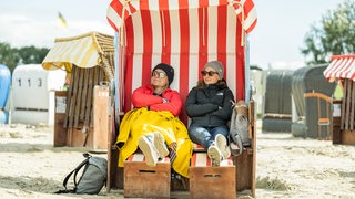 Zwei Frauen mit Sonnenbrillen sitzen in einem Strandkorb.
