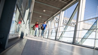 Eine Frau und ein Mann laufen am Flughafen in Bremen über die Fluggastbrücke.