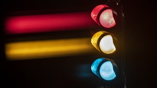 Eine Ampel zeigt die Lichter in gruen, gelb und rot 