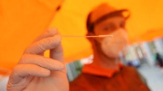 Ein Mitarbeiter hält in einem Testcenter Tupfer, mit dem ein Abstrich für einen Coronatest gemacht wird.