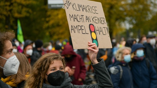 Auf einer Klimademonstration: Frau mit Plakat: Die Klimakrise macht an keiner Ampel halt