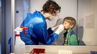 Ein Mitarbeiter eines Testzentrums führt einen Corona-Test an einem Kind durch. 