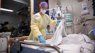 Krankenpflegerin Meryl Meister versorgt in einem Patientenzimmer eines abgetrennten Bereichs für Covid-19 Patienten einer Intensivstation des Klinikum Stuttgart, einen Covid-19-Patienten, der im künstlichen Koma liegt und beatmet wird. (zu dpa "Auf der Corona-Intensivstation") 