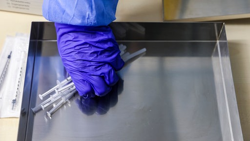 Eine Mitarbeiterin der Malteser nimmt sich fertige Spritzen mit Impfstoff von Biontech
