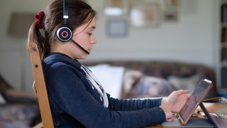 Eine Teenagerin lernt mit Kopfhörern am iPad