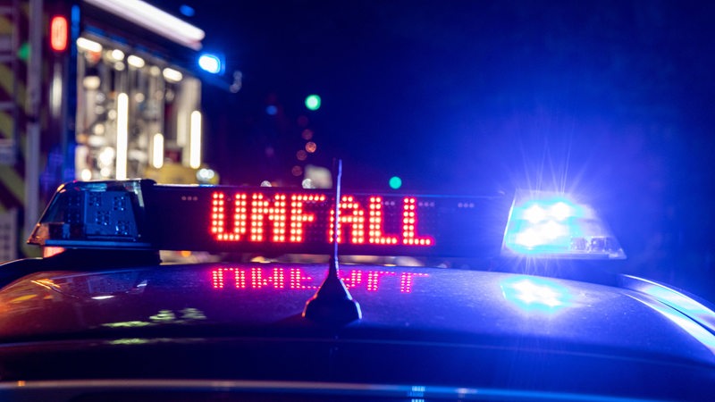 Ein Polizeiauto auf dessen Dach ein Blaulicht blinkt ist im Dunkeln zu sehen.