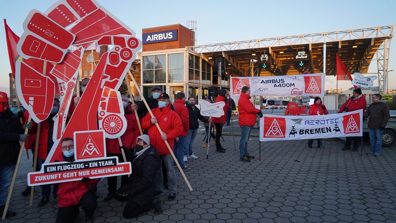 Vor dem Hamburger Airbus-Werk protestieren Mitarbeiter mit Schildern und Plakaten gegen Umstrukturierungspläne. 
