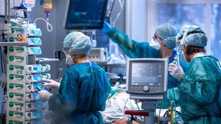 Ärzte und Pflegekräfte betreuen Patienten in einem der Behandlungszimmer der Intensivstation in der Universitätsmedizin Rostock.