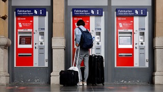 Ein junger Mann steht vor einem Fahrkartenautomaten der Deutschen Bahn