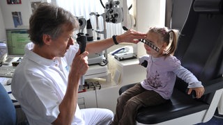 Ein Augenarzt bei der Untersuchung eines Kindes