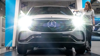 Eine Mitarbeiterin von Mercedes-Benz kontrolliert einen Wagen vor der Ausfahrt aus dem Mercedes-Werk in Bremen.