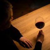 Eine Frau sitzt mit einem Glas Rotwein an einem Tisch.