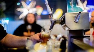 Ein Kneipenwirt zapft in einer Gaststätte Bier.