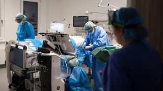 Ärzte und Pflegekräfte betreuen Patienten in einem Behandlungszimmer einer Corona-Intensivstation.