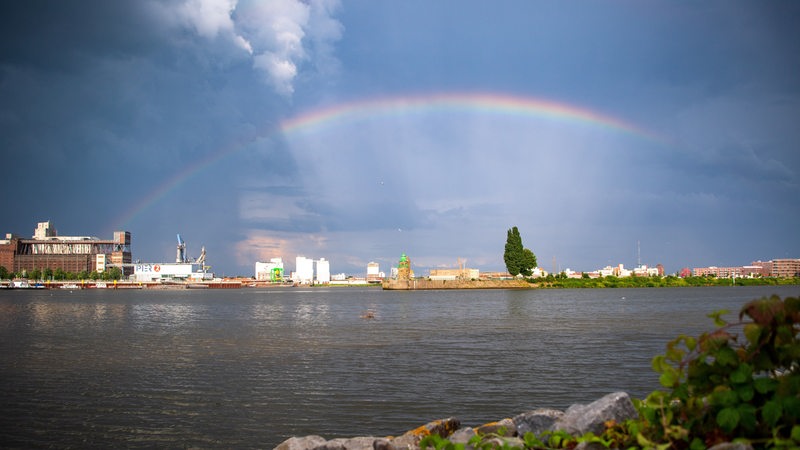 Ein Regenbogen spannt sich über die Weser und die Überseestadt.