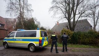 Polizisten stehen vor einem Haus