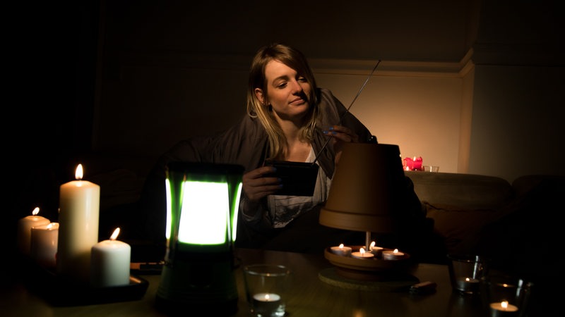  Eine junge Frau sitzt, umgeben von zahlreichen Kerzen und Teelichtern, am 29.01.2020 in einer Wohnung in Wittenberge auf Grund eines Stromausfalls im Dunkeln und hoert Radio (gestellte Szene).