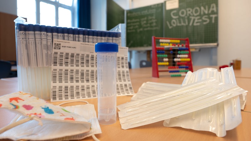 Ein komplettes, unbenutztes Set des sogenannten "Lolli-Test" (PCR-Pooltest) steht in einem Grundschul-Klassenzimmer