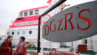 Mitglieder der Crew des Seenotrettungskreuzers "Hans Hackmack" unterhalten sich vor dem Schiff der Deutschen Gesellschaft zur Rettung Schiffbrüchiger (DGzRS).