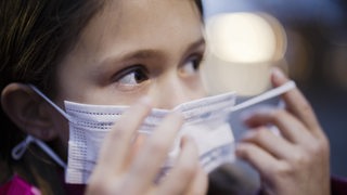 Ein Grundschülerin zieht ihren Mund-Nasen-Schutz auf
