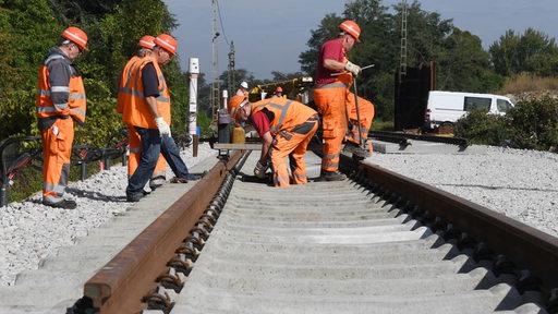 Bauarbeiter erneuern Gleise einer Zugstrecke.
