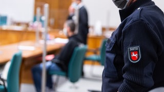Ein Angeklagter sitzt vor Prozessbeginn im Saal vom Landgericht Lüneburg
