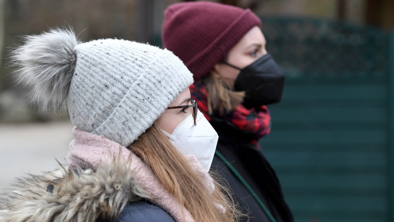 Zwei junge Frauen mit FFP 2 Masken im Freien und Winterbekleidung