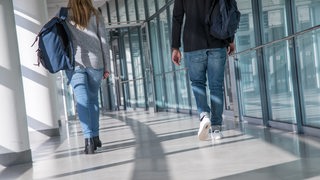Eine Frau und ein Mann laufen in Bremen durch den Flughafen, um zu ihrem Gate zu gelangen.