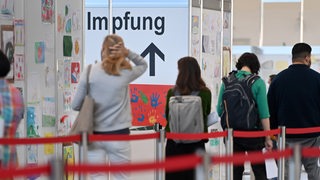 Menschen stehen in einer Schlange und warten auf ihre Impfung.
