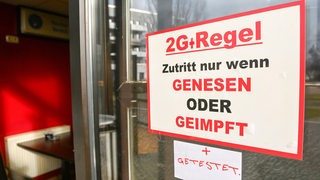 Ein Schild an einer Gaststätte verweist auf die 2G-plus-Regel beim Betreten der Innenräume.