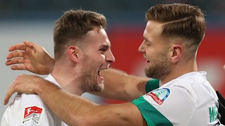 Die Werder-Stürmer Marvin Ducksch und Niclas Füllkrug fallen sich jubelnd in die Arme.