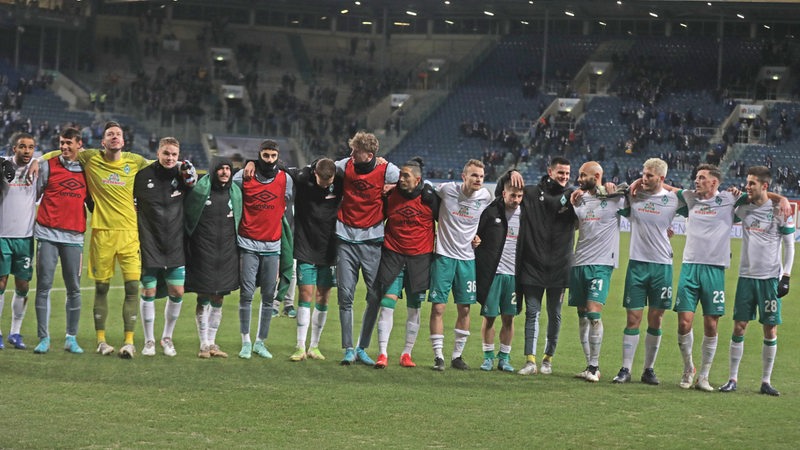 Die Werder-Spieler stehen aufgereiht Arm in Arm nebeneinander vor dem Bremer Fanblock im Ostseestadion und feiern den Sieg.