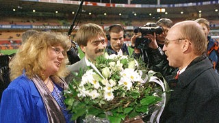 Werder-Manager Willi Lemke überreicht einem Paar auf dem Rasen des Weserstadions einen großen Blumenstrauß, das gerade dort geheiratet hatte.
