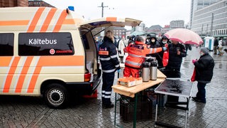 Karin Stelljes, Teamleiterin beim Kältebus der Johanniter, reicht an Heiligabend auf dem Vorplatz am Hauptbahnhof eine mit Lebensmitteln gefüllte Tüte an einen bedürftigen Menschen