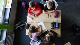 Schülerinnen schreiben etwas in Hefte in einem  Klassenzimmer 