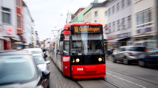 Eine Straßenbahn fährt zwischen Autos durch die Innenstadt.