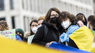 Zwei Frauen halten sich bei einer Demonstration gegen den Ukraine-Krieg im Arm.