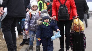 Kinder mit gepackten Sachen, Teddy an der Hand