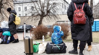 Geflüchtete aus der Ukraine an einer Bahnstation in Przemysl in Polen. Ein kleines Kind sitzt auf einer Reisetasche.