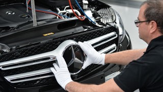 Ein Mitarbeiter von Mercedes-Benz bringt den Stern an ein C-Klasse Modell an. 