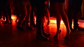 In rotes Licht getauchte Beine von feiernden Menschen