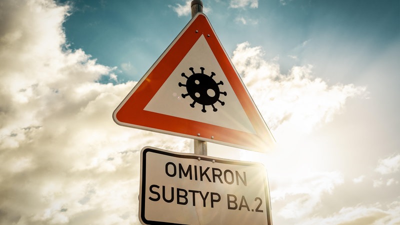 Auf einem Verkehrsschild steht die Aufschrift: "Omikron Subtyp BA.2".