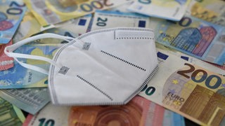Eine FFP2-Maske liegt auf Geldscheinen