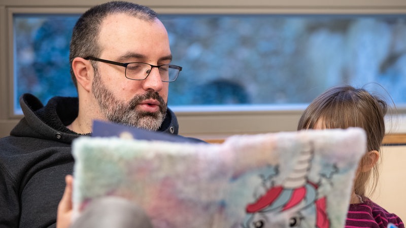 Ein Erzieher liest einem Kind aus einem Buch vor.