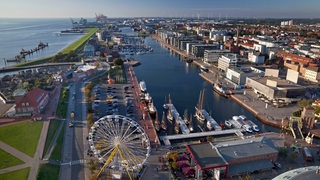 Eine Luftaufnahme zeigt ein Hafenbecken mit einem Riesenrad.