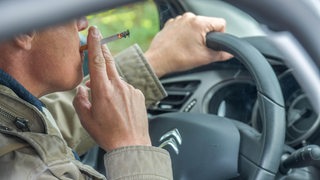 Ein Mann raucht eine Zigarrette im Auto