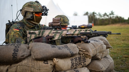 Soldaten der Bundeswehr hocken mit dem Sturmgewehr vom Typ G36 A2 während einer Vorführung in einer Stellung.