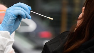 Eine Hausärztin nimmt einen Abstrich von einer Patientin für einen PCR-Test auf das Corona-Virus 